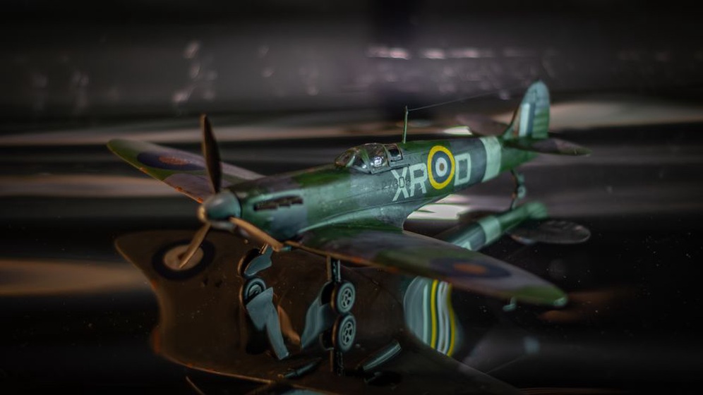 Un maquettiste peint soigneusement une miniature d’avion